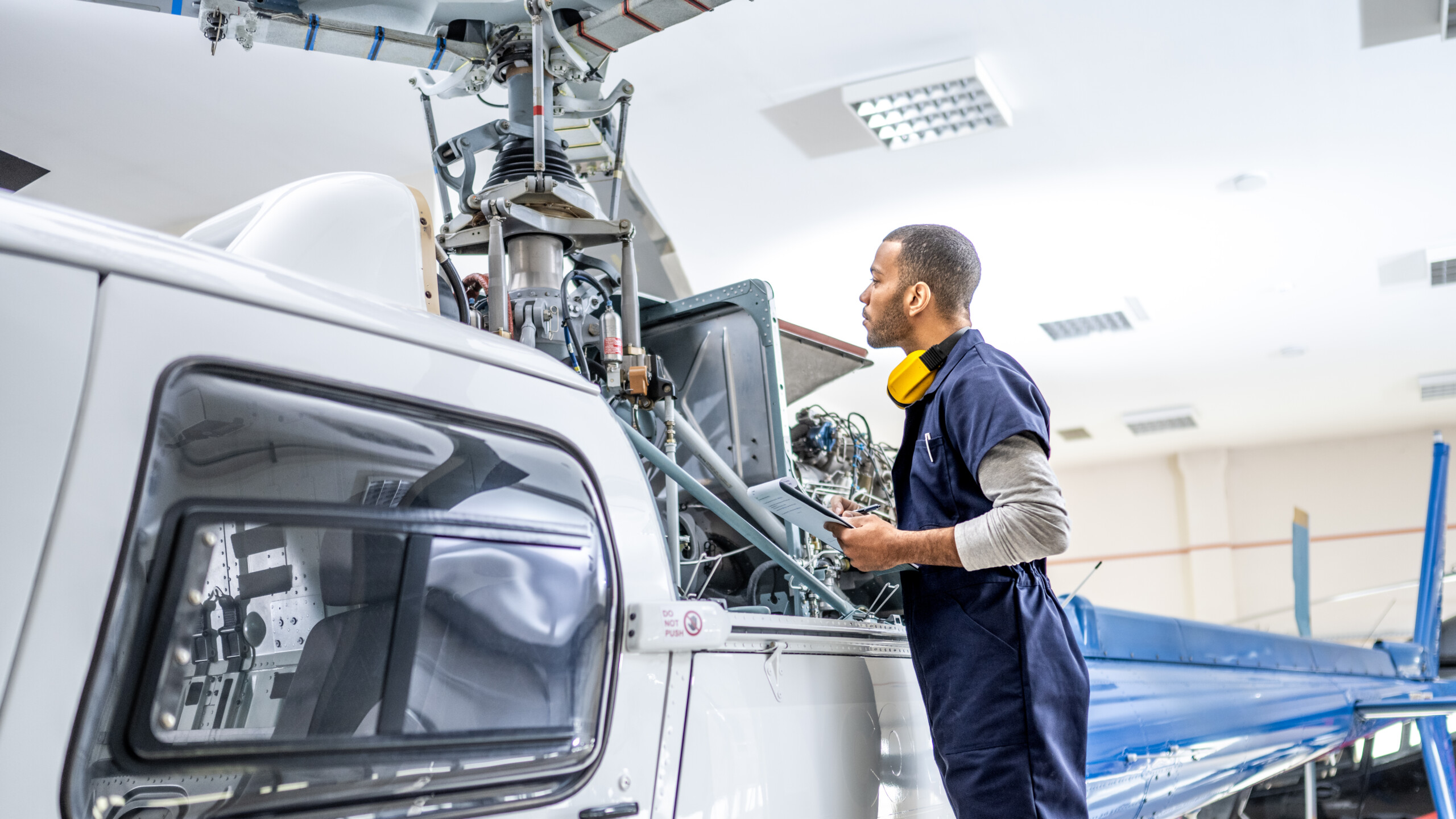 African American mechanic standing near jet and fixing propeller engine, side view